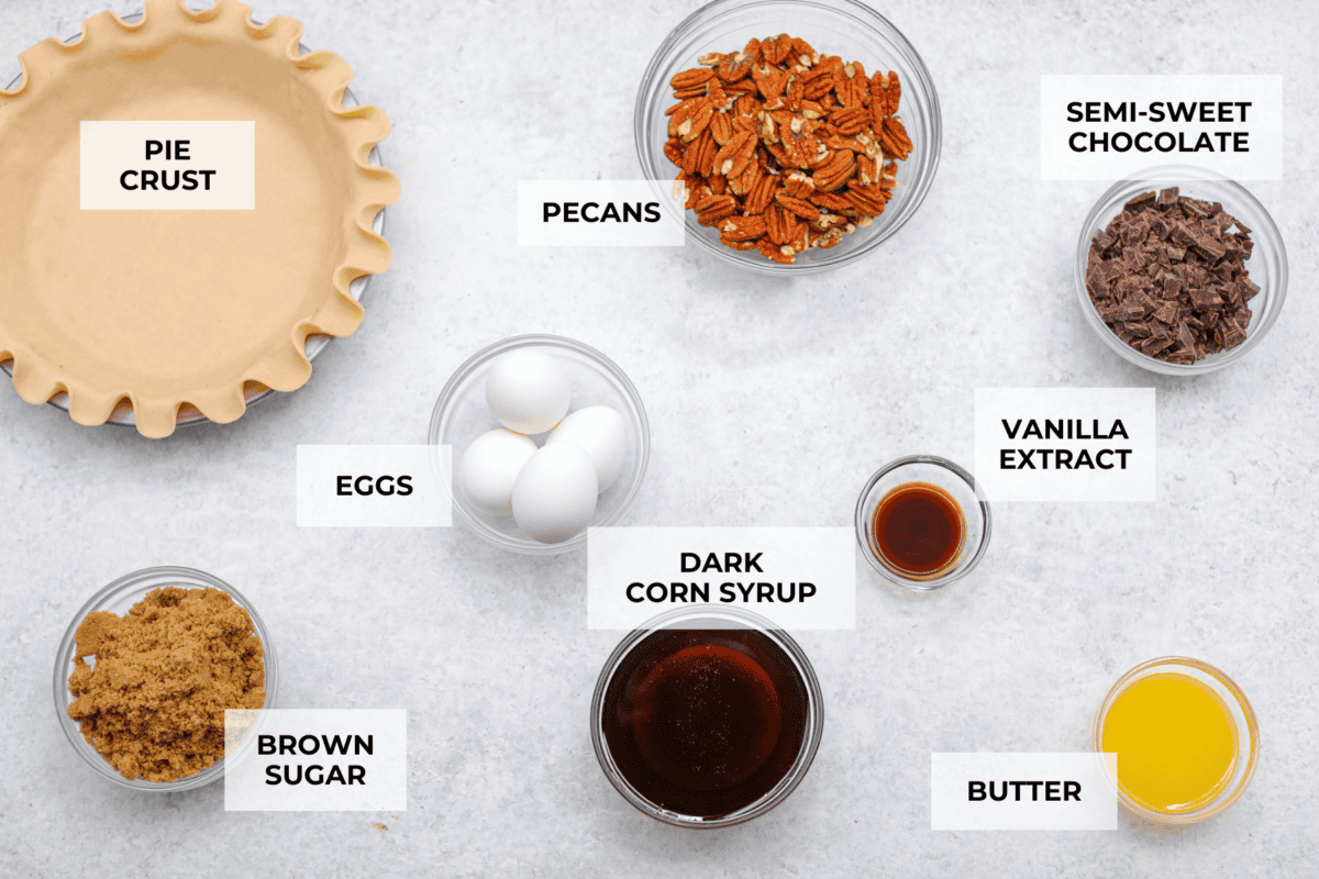 Chocolate pecan pie is a sweet, decadent dessert with a buttery crust filled with gooey caramel, crunchy pecans, and rich chocolate. It's the perfect pie to share this Thanksgiving. It will knock your family's socks off! Overhead shot of labeled ingredients.