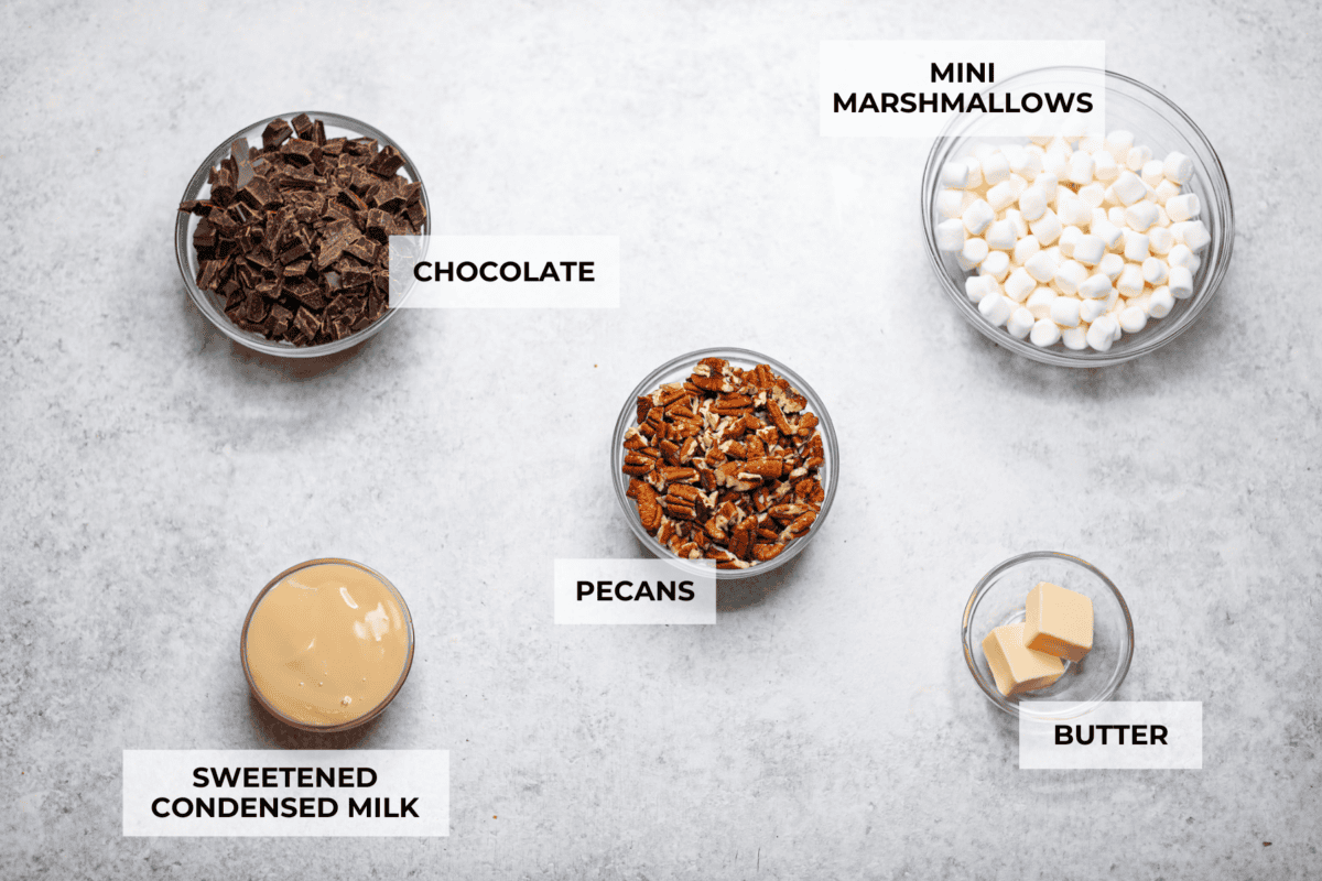 These decadent rocky road bars are the best no-bake treat that you can whip up in no time when that sweet tooth hits. Fudgy chocolate, soft marshmallows, and chewy pecans combine to make the most amazing dessert. Overhead shot of labeled ingredients.