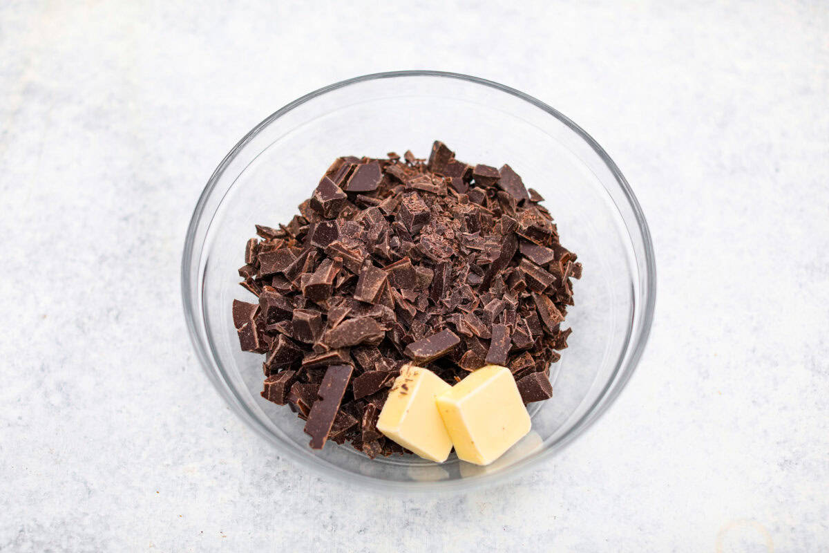 These decadent rocky road bars are the best no-bake treat that you can whip up in no time when that sweet tooth hits. Fudgy chocolate, soft marshmallows, and chewy pecans combine to make the most amazing dessert. Overhead shot of chocolate and butter in a glass bowl.
