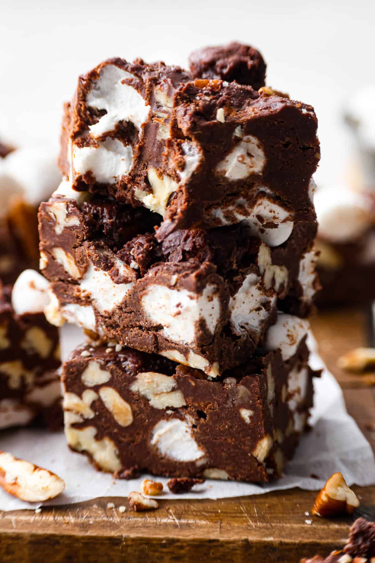 These decadent rocky road bars are the best no-bake treat that you can whip up in no time when that sweet tooth hits. Fudgy chocolate, soft marshmallows, and chewy pecans combine to make the most amazing dessert. Close up shot of stacked rocky road bars.