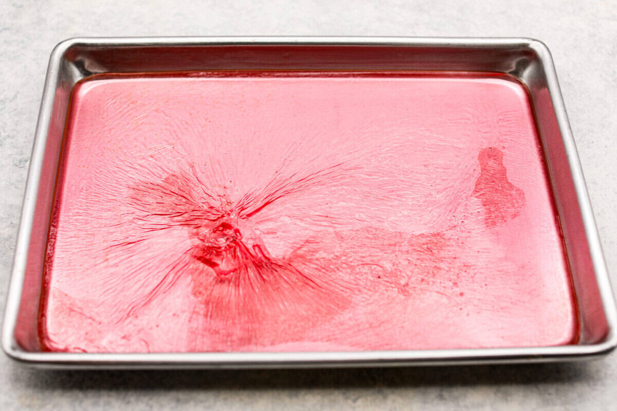 Homemade cherry cordials are a tasty, nostalgic treat! They're made with sweet cherries that are coated in a rich chocolate shell. Make them for Christmas or Valentine’s Day, and watch them disappear! Overhead shot of syrup cooling on a baking sheet.