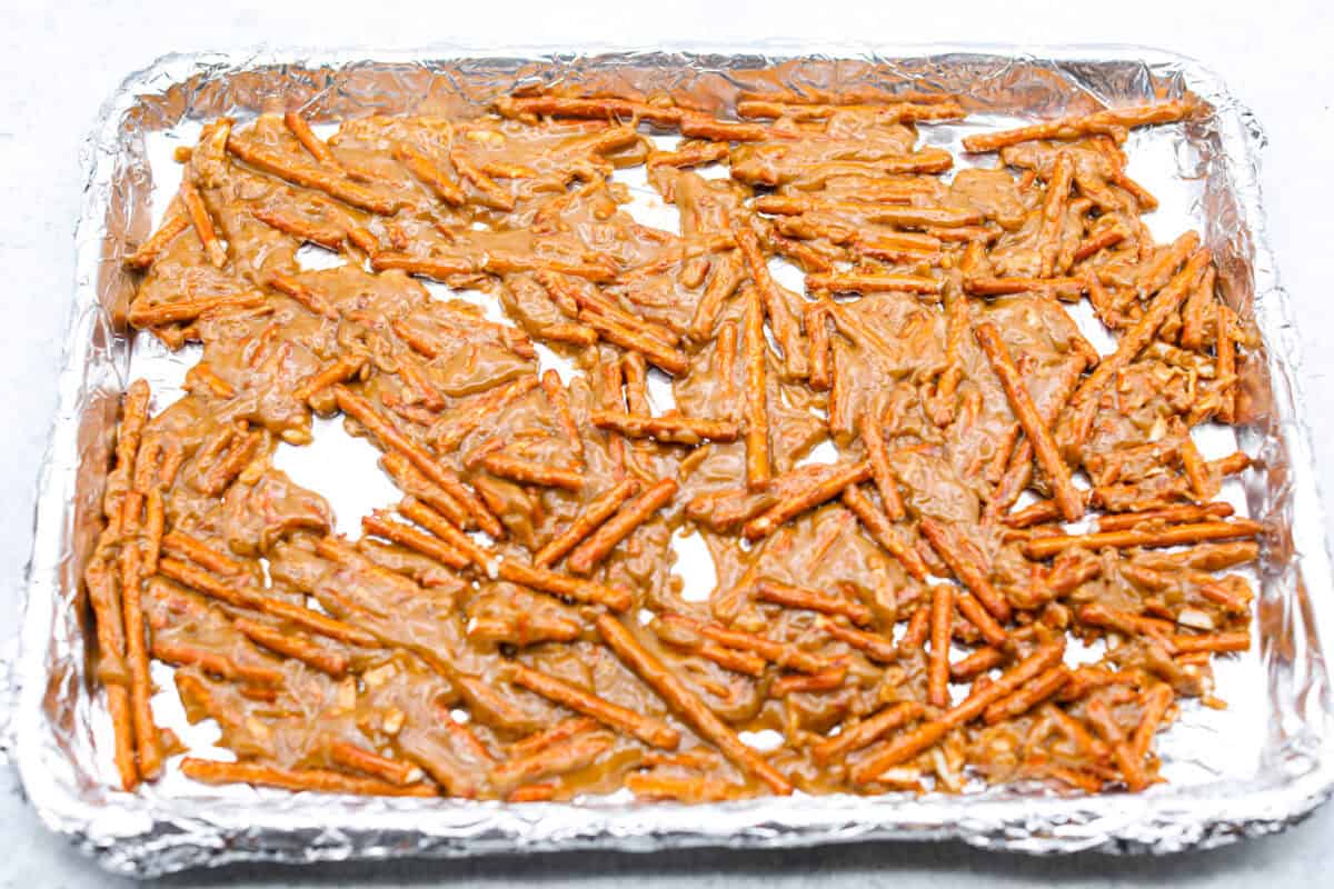 Pretzel Christmas Crack is the best holiday treat! This addictive combination of salty pretzels, rich toffee, and chocolate is sure to be a hit at any party or gathering. Overhead shot of pretzels and caramel spread out on a baking sheet.