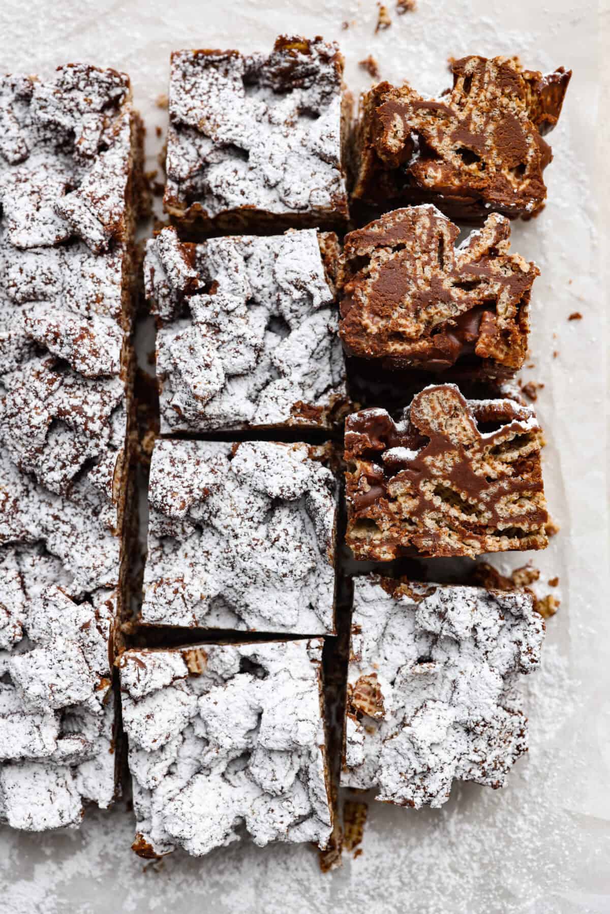 These tasty Muddy Buddy Bars are a fun twist on the classic snack mix. Crunchy cereal is surrounded by sweet marshmallows, chocolate, and peanut butter. These bars are a fun new way to enjoy this classic flavor combination. Overhead shot of muddy buddy bars.