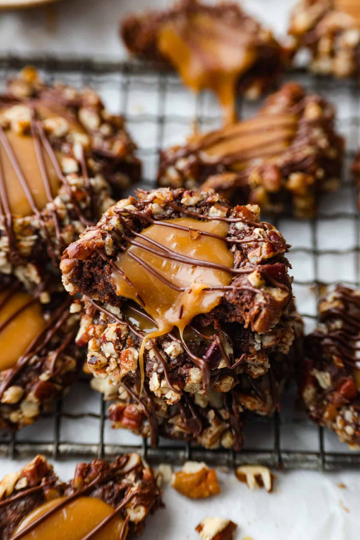 Turtle Cookies are a baked, bite-size brownie loaded with pecans, then filled with a creamy caramel center for a rich, decadent holiday cookie! These turtle cookies are always a huge hit and are gone in minutes. Close up shot of a stack of turtle cookies.
