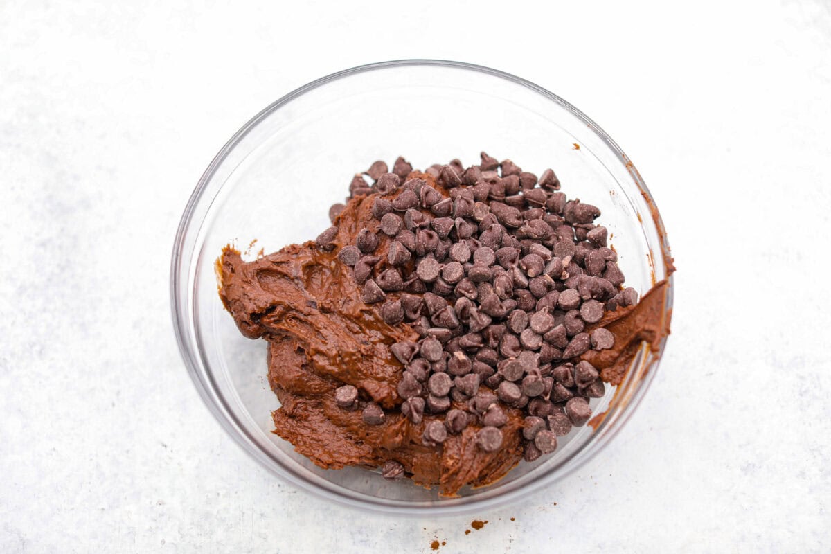 Black bean brownies are rich, fudgy, and packed with chocolatey goodness! They have a slightly denser texture, similar to a protein bar, but still satisfy that brownie craving. While adults may notice a slight difference from traditional brownies, kids won’t be able to tell! Overhead shot of black bean brownie batter in a mixing bowl with chocolate chips added to it.