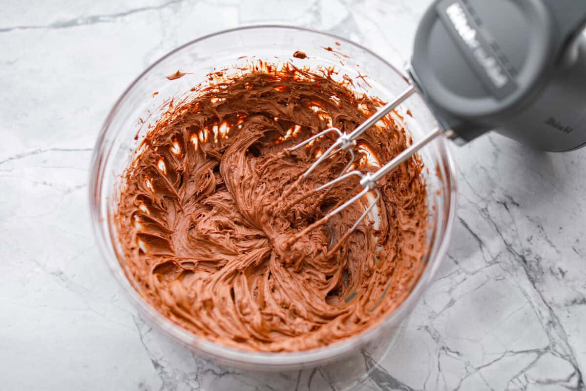 Rich, fudgy, and packed with deep chocolate flavor, Guinness Brownies are a must-try for any dessert lover! The stout beer enhances the cocoa, adding a subtle, malty depth of flavor that makes these brownies rich and irresistibly delicious. Overhead shot of someone using a hand mixer to whip up the chocolate chip mixture to make a fluffy ganache.